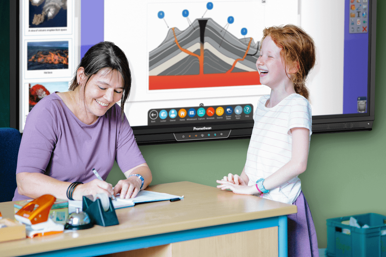 A teacher and a young girl laughing in front of Promethean's ActivPanel