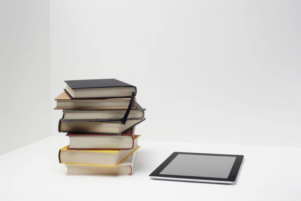 Image of a stack of books with an e reader next to it.