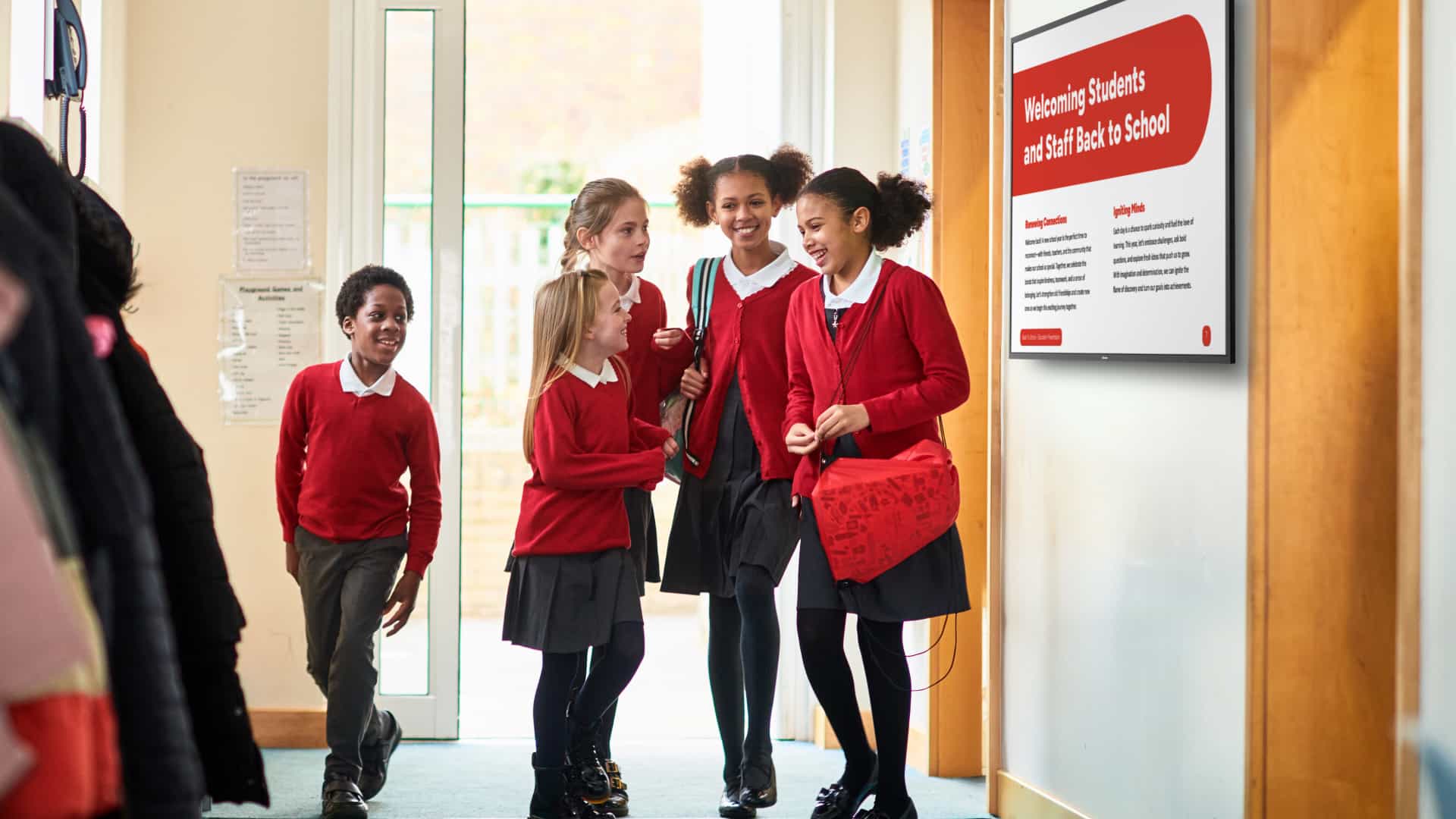 Students walk in a hallway between classes while an ActivPanel D-Series shows announcements.