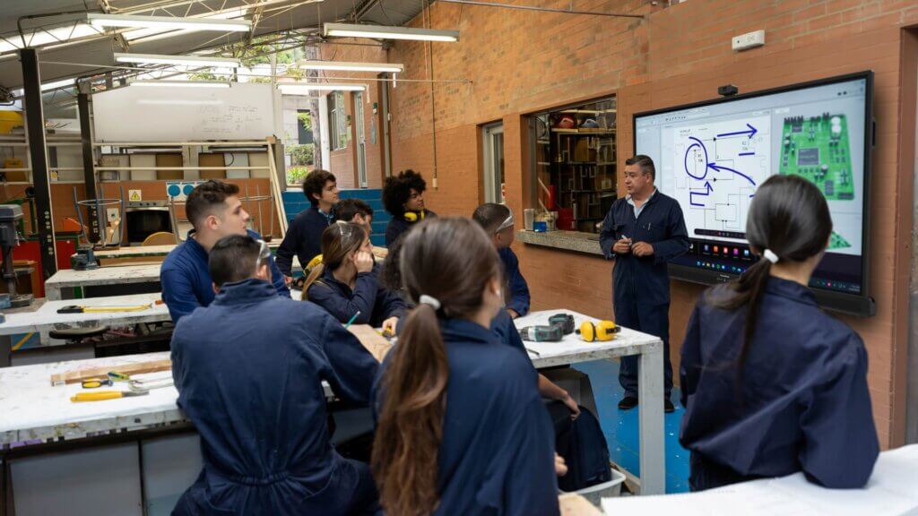 A teachers uses the ActivPanel 10 Premium ActivPen 2 and All-in-one Remote accessories while teaching a workshop class.